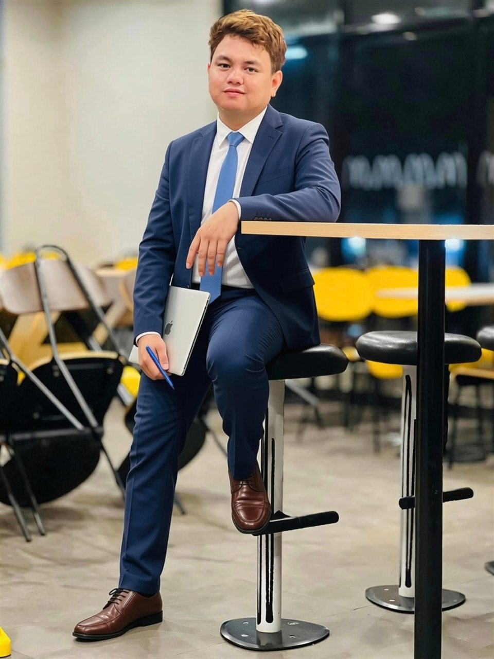 Win, founder of HeyWin, in a navy suit holding a laptop